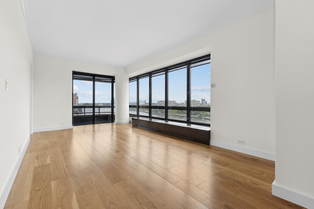 spare room with a view of city, wood finished floors, and baseboards