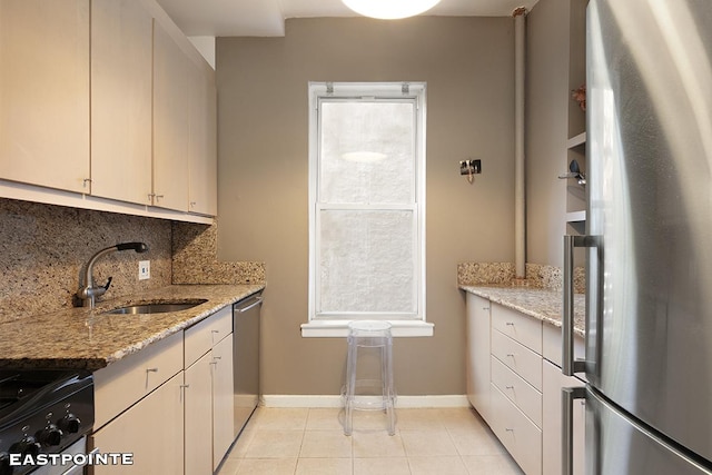 kitchen with light tile patterned flooring, stainless steel appliances, a sink, baseboards, and tasteful backsplash