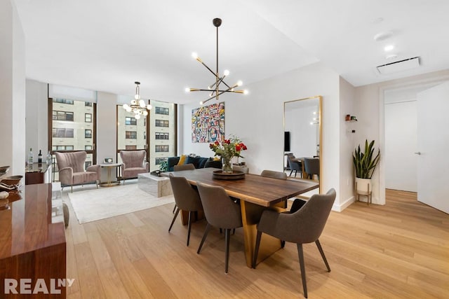 dining space with light hardwood / wood-style floors and a chandelier