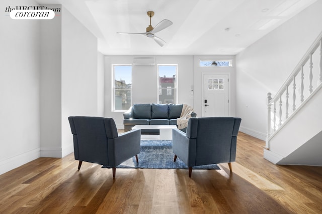 living room featuring ceiling fan, hardwood / wood-style floors, and a wall mounted air conditioner