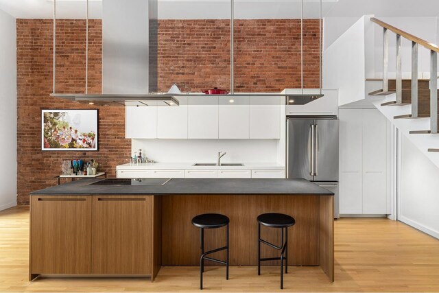 123 Prince St Unit 1, New York City, NY 10012 - kitchen featuring wall chimney range hood, high end fridge, black electric stovetop, a sink, and modern cabinets