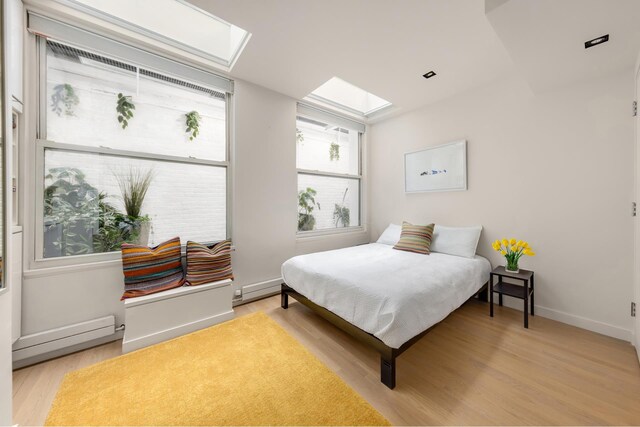 123 Prince St Unit 1, New York City, NY 10012 - bedroom featuring a skylight, light wood-type flooring, a baseboard heating unit, and baseboards
