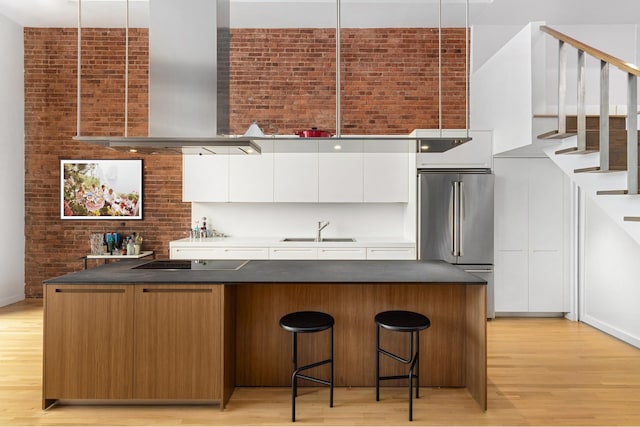 123 Prince St Unit 1, New York City, NY 10012 - kitchen featuring wall chimney range hood, high end fridge, black electric stovetop, a sink, and modern cabinets