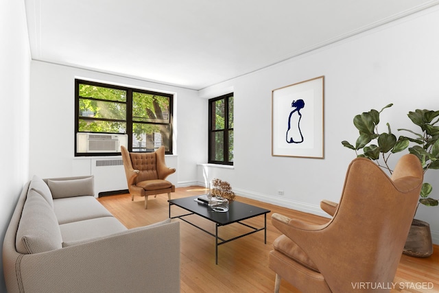 living area with radiator heating unit, wood finished floors, baseboards, and cooling unit