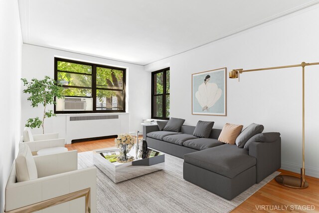 222 E 35th St Unit 2F, New York City, NY 10016 - living area with radiator heating unit, wood finished floors, and cooling unit