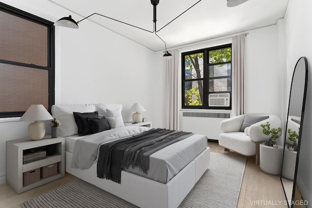 bedroom with radiator, wood finished floors, and cooling unit
