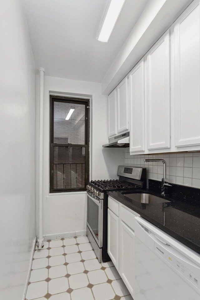 kitchen featuring white cabinetry, gas range, dishwasher, dark stone counters, and sink