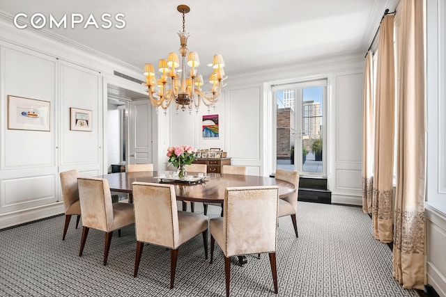 dining area with ornamental molding, a decorative wall, and a notable chandelier