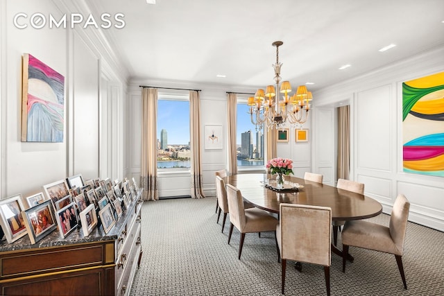 dining room with light carpet, an inviting chandelier, crown molding, and a decorative wall