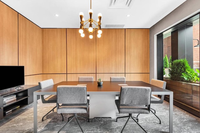 dining area featuring wood walls and an inviting chandelier