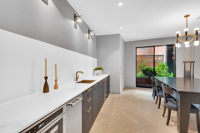 kitchen with a sink, modern cabinets, light countertops, a chandelier, and baseboards