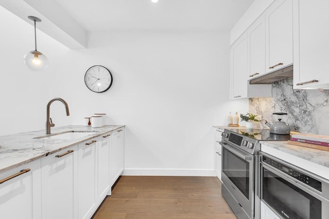 kitchen featuring appliances with stainless steel finishes, white cabinetry, decorative light fixtures, and sink