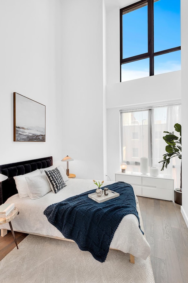 bedroom featuring a towering ceiling and wood finished floors
