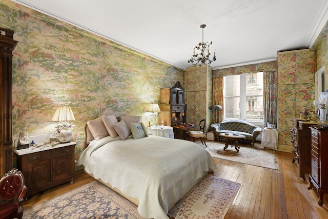 bedroom with an inviting chandelier, ornamental molding, and light hardwood / wood-style floors