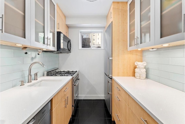 kitchen featuring appliances with stainless steel finishes, dark tile patterned floors, light brown cabinets, sink, and backsplash