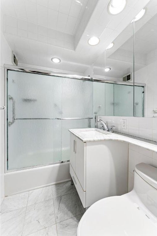 full bathroom featuring combined bath / shower with glass door, vanity, and toilet