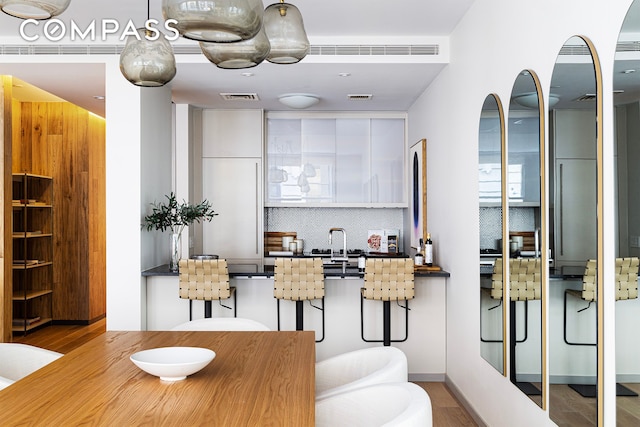 kitchen featuring visible vents, backsplash, and white cabinetry