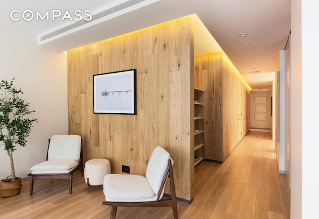 sitting room with light wood finished floors and wood walls