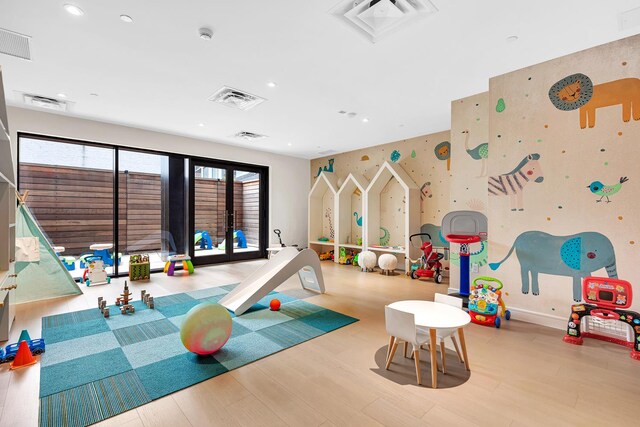 game room featuring wood finished floors, visible vents, and wallpapered walls