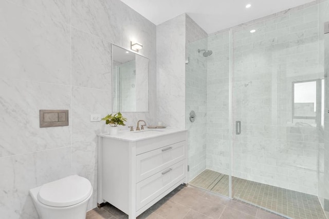 bathroom with tile walls, vanity, a shower with door, and toilet