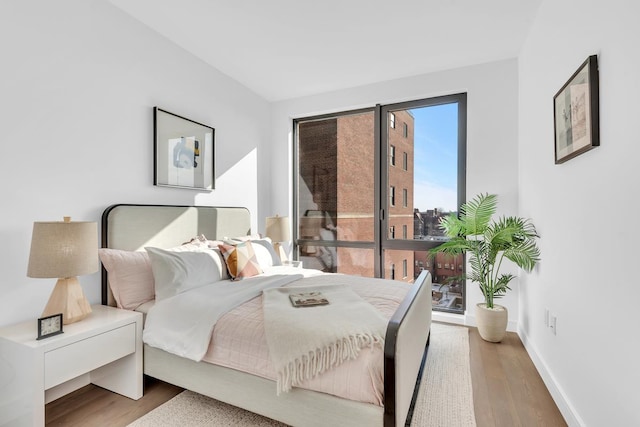 bedroom with access to exterior, baseboards, and wood finished floors