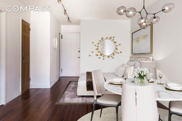 dining room featuring track lighting, baseboards, wood finished floors, and a chandelier