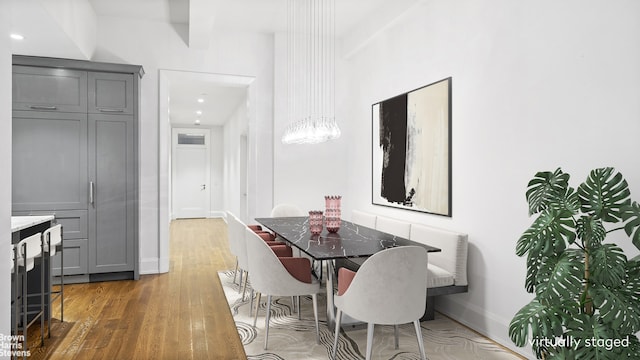 dining space featuring baseboards, a notable chandelier, and wood finished floors