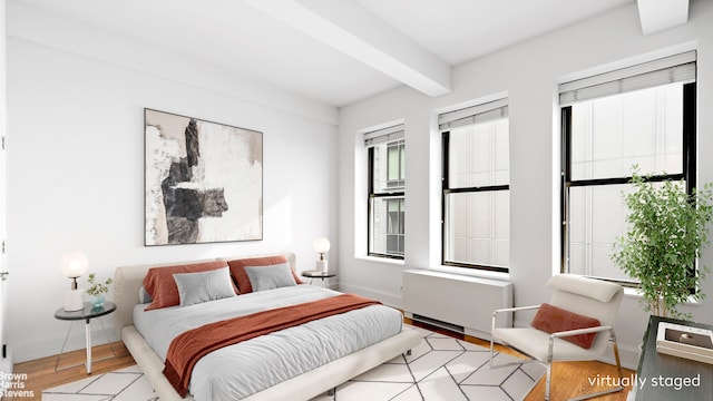 bedroom with beamed ceiling, radiator heating unit, wood finished floors, and baseboards