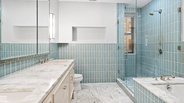 full bath featuring double vanity, a stall shower, a sink, tile walls, and toilet