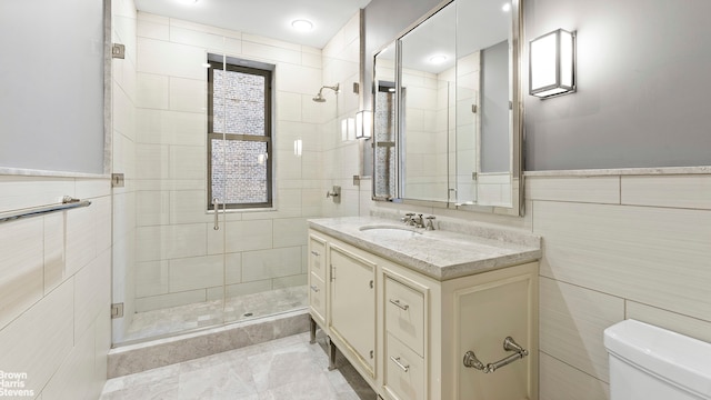 bathroom featuring vanity, toilet, tile walls, and a shower stall