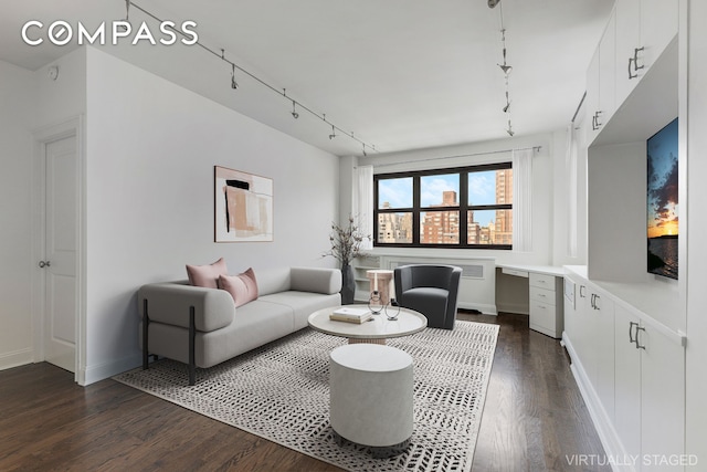 living area with track lighting, baseboards, dark wood-style flooring, and built in desk