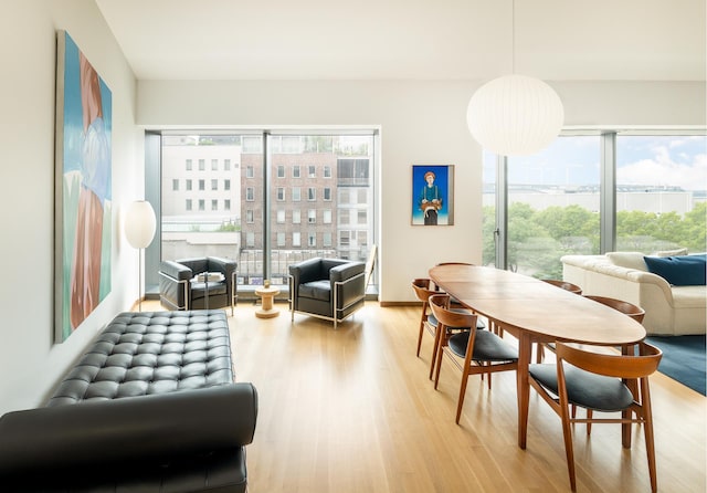 dining room with light wood-type flooring, a view of city, and a healthy amount of sunlight