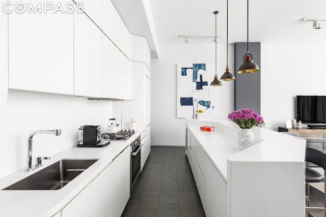 kitchen featuring appliances with stainless steel finishes, white cabinetry, sink, hanging light fixtures, and a kitchen breakfast bar