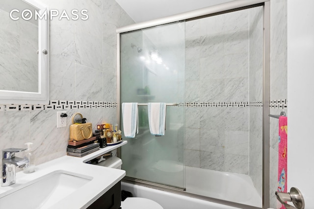 bathroom with vanity, bath / shower combo with glass door, tile walls, toilet, and tasteful backsplash