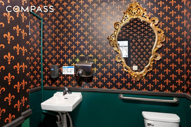 397 5th Ave, New York City, NY 11215 - bathroom featuring wallpapered walls, wainscoting, toilet, and a sink