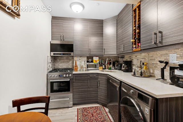 kitchen featuring stainless steel gas range oven, a sink, backsplash, washer / dryer, and dark brown cabinets