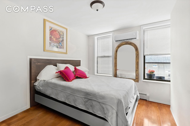 bedroom featuring wood finished floors, a wall mounted air conditioner, baseboards, and a baseboard radiator