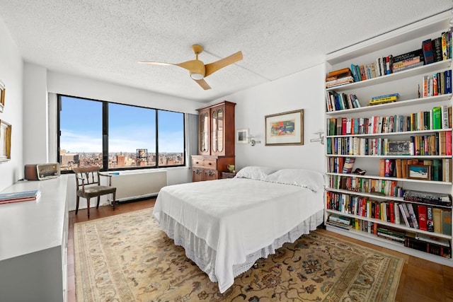 bedroom featuring ceiling fan, light hardwood / wood-style flooring, and a textured ceiling