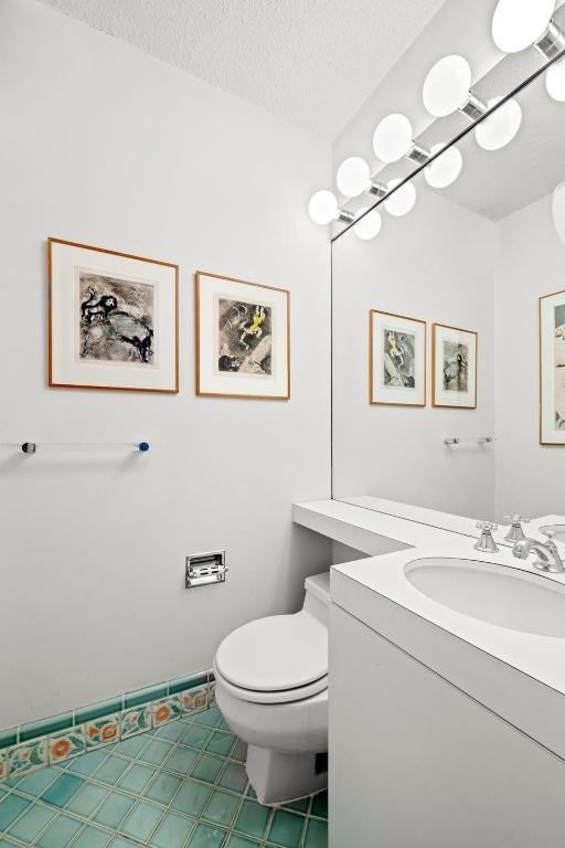 bathroom featuring vanity, tile patterned floors, a textured ceiling, and toilet