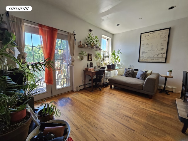 living room with a wealth of natural light, french doors, wood finished floors, and a baseboard radiator