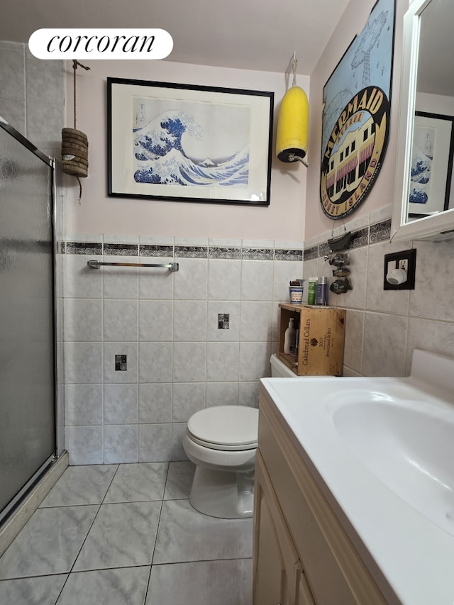 563 20th St, New York City, NY 11218 - bathroom featuring tile walls, a shower stall, vanity, toilet, and a wainscoted wall