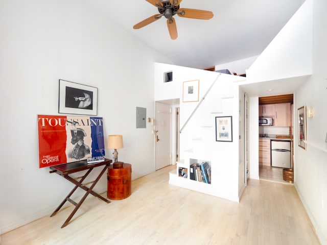 interior space featuring ceiling fan, high vaulted ceiling, electric panel, and light hardwood / wood-style floors