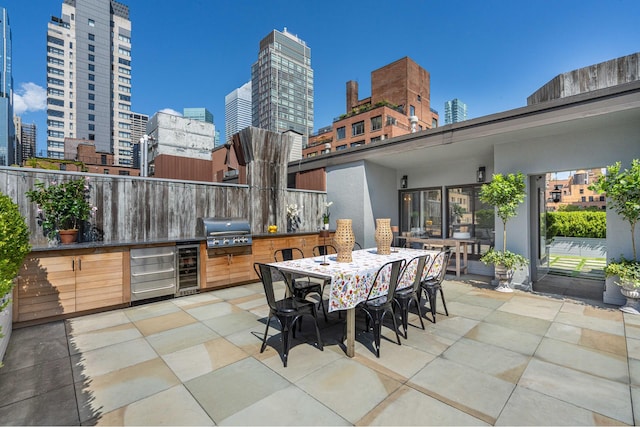 view of patio / terrace with a view of city, beverage cooler, exterior kitchen, and grilling area