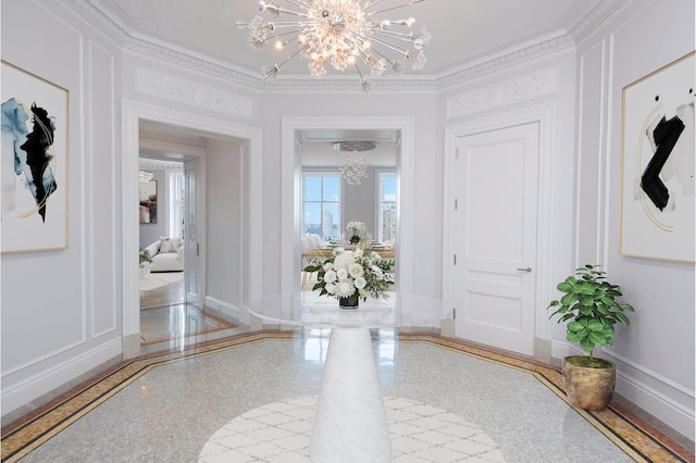 entryway featuring baseboards, ornamental molding, an inviting chandelier, granite finish floor, and a decorative wall