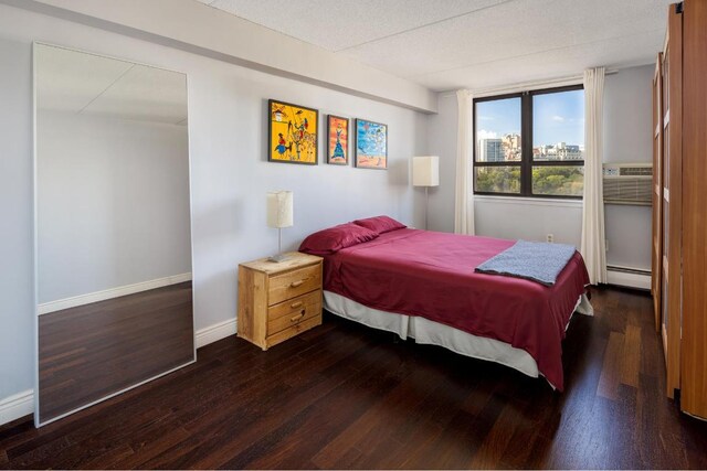 bedroom with a baseboard heating unit and dark hardwood / wood-style flooring