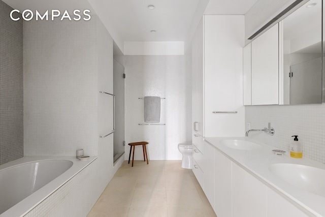 bathroom featuring toilet, a sink, tile patterned flooring, walk in shower, and a bath