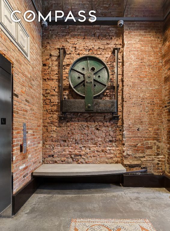 interior space with concrete flooring, elevator, and brick wall