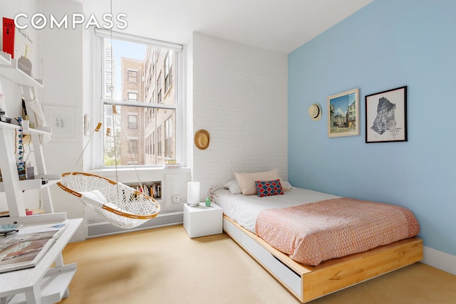 carpeted bedroom featuring brick wall