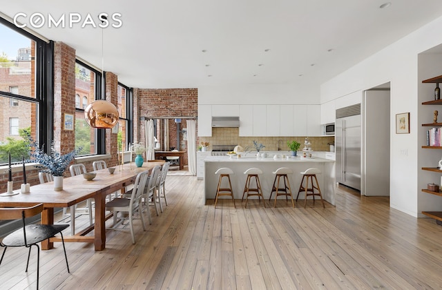 kitchen featuring tasteful backsplash, light countertops, light wood-style flooring, white cabinets, and modern cabinets