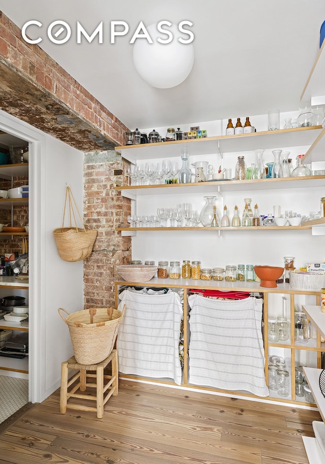 bar with a dry bar, wood finished floors, and brick wall